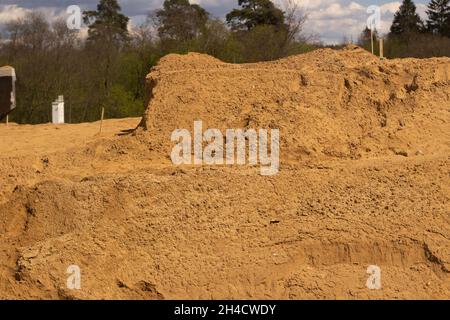 Sandplattform. Sand in die Basis legen. Viel Baumaterial. Bau einer Straßenkreuzung. Stockfoto