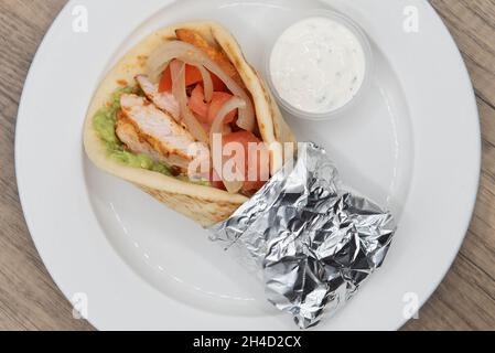 Ansicht von oben auf eine geladene Tikka Chicken Fajita-Packung voller Füllungen in einem frisch gebackenen Pita-Fladenbrot. Stockfoto