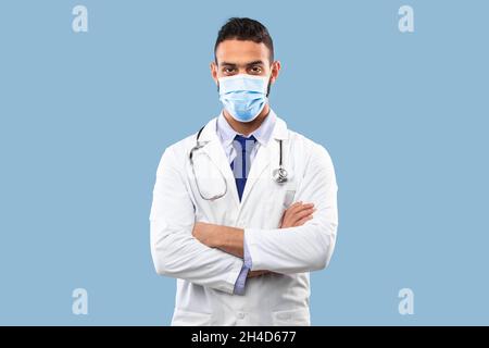 Middle Eastern Male Doctor Trägt Schutzmaske Über Blauem Hintergrund Stockfoto