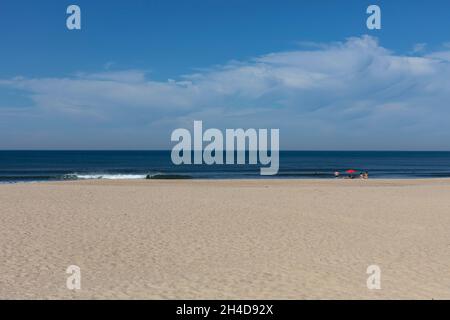 Leerer Strand mit rotem Sonnenschirm und zwei Strandbesuchern, nicht erkennbar) in Espino Stockfoto