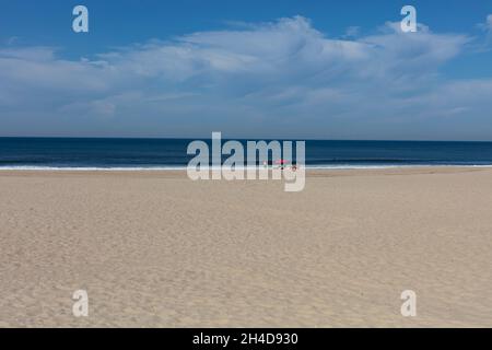 Leerer Strand mit rotem Sonnenschirm und zwei Strandbesuchern, nicht erkennbar) in Espino Stockfoto