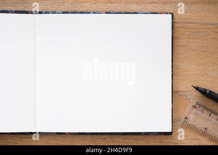 Leerer Hintergrund oder Vorlage für Notizbücher oder Skizzenbücher. Flach lag auf einem Holzschreibtisch, Bullet Journal oder Journaling Konzept mit leerer weißer Seite Stockfoto