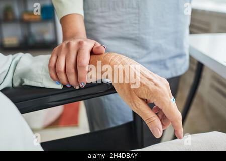 Nahaufnahme des Porträts einer Betreuerin, die die Hände hält, während eine ältere Frau den Rollstuhl benutzt, Platz kopieren Stockfoto