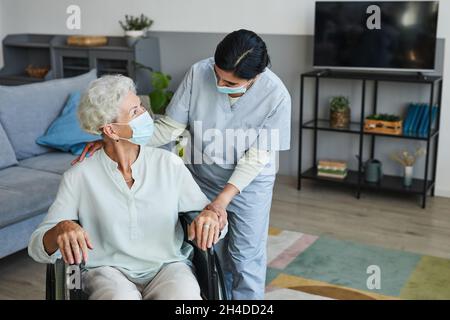 Porträt einer Krankenschwester, die einer älteren Frau im Rollstuhl zu Hause oder im Altersheim assistiert, Kopierraum Stockfoto