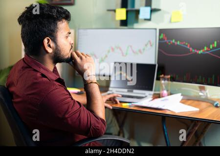 Seitenansicht des Trader, der den Aktienmarkt analysiert, indem er Charts in mehrblassigen Monitoren betrachtet oder Strategien im Home Office entwickelt - Konzept der Untersuchung von Eigenkapital Stockfoto