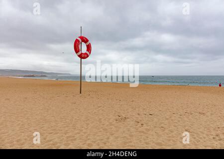 Leerer Strand von Nazaré in Portugal. Rettungsring am Strand zur Sicherheit Stockfoto