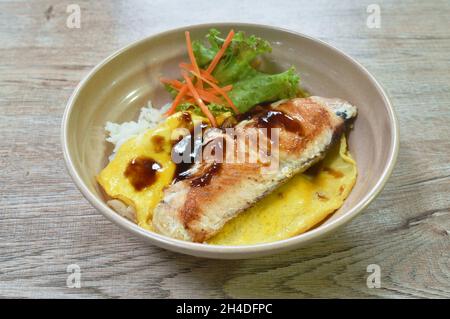 Gegrillter Lachs mit Eiersoße Teriyaki, die auf japanischen Reis in einer Schüssel übergeht Stockfoto