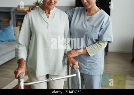 Ausgeschnittene Aufnahme einer Krankenschwester, die älteren Frauen mithilfe von Gehhilfen im Altersheim hilft, Kopierraum Stockfoto