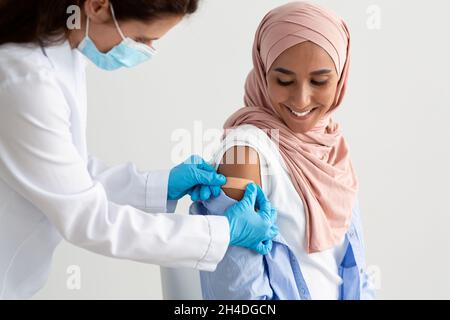 Glückliche Muslimische Frau, Die In Der Klinik Gegen Covid-19 Geimpft Wird Stockfoto