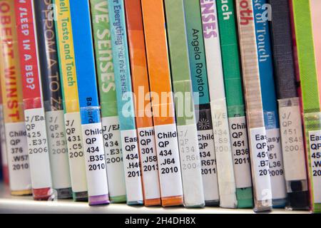 Nahaufnahme von Büchern mit Klassifizierungsrufnummern der Library of Congress auf Buchstacheln im Regal in einer kinderwissenschaftlichen Abteilung einer öffentlichen Bibliothek Stockfoto