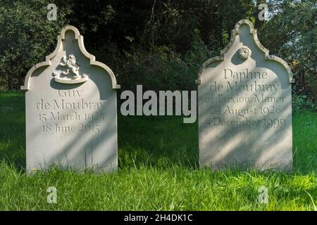 Zwei passende Grabsteine mit verzierten Schnitzereien für Guy & Daphne de Moubray auf Gras mit dunklem Heckenhintergrund, St. Lawrence Church Knodishall, Suffolk Stockfoto