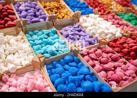 Handgemachte Seifen in verschiedenen Formen und Farben in Holzkisten zum Verkauf. Niedliche bunte kleine organische Tier geformte Seifenstücke für Kinder. Selektiver Fokus. Stockfoto