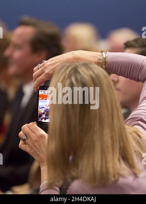 Ein konservativer Delegierter fotografiert Premierminister David Cameron während der Konferenz der Konservativen Partei 2014 im ICC Birmingham. Stockfoto