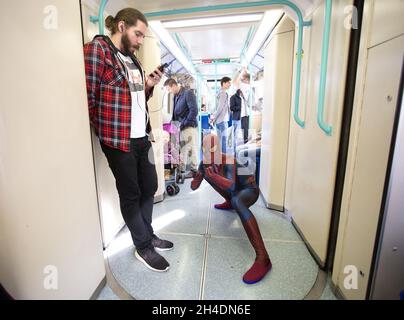 Ein Cosplayer, gekleidet als Spiderman, im DLR-Zug zur MCM London Comic Con in London Excel am Sonntag, den 25. Oktober. Stockfoto