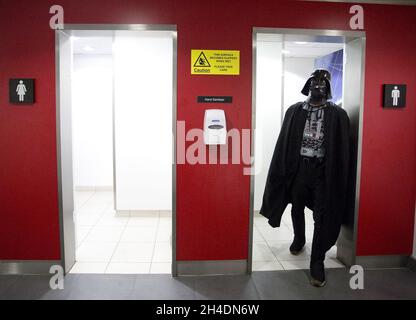 Ein Cosplayer, der als Star Wars Darth Vader verkleidet ist, verlässt am Sonntag, den 25. Oktober, auf der MCM London Comic Con in London Excel die Herrentoilette. Stockfoto