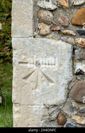 Ein Vermesser, der auf dem Eckstein der Church of St Mary & St Peter Kelsale, Suffolk, Großbritannien, ansetzt Stockfoto