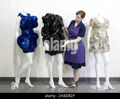 Die Hausassistentin Lucy Bishop verleiht den Kleidern der Sängerin Bjšrk für die Auktion „Passion for Fashion“ am 14. Juni bei Kerry Taylor Auctions im Süden Londons den letzten Schliff. (Links) Los 350, Bjšrk's Iris van Herpen Couture Electric-blue Acrylkleid, getragen für die 'Biophilia' Tour, 2012, das Design basiert auf dem 'Eskapismus' Frühjahr-Sommer, Kollektion 2011 (Schätzung £4,000-6,000) (Mitte) Los 351 : Bjšrk's Iris van Herpen 'Snake' Kleid, 'Capriole' Kollektion, Herbst-Winter, 2011-12 (Schätzung £4,000-6,000) (rechts) Los 347 : Bjšrk Iris van Herpen Couture cremefarbenes, schillerndes Acrylkleid, w Stockfoto