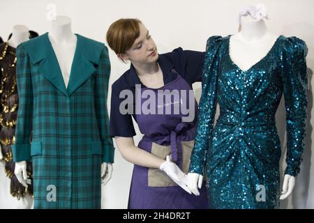 Die Auktionsassistentin Lucy Bishop bringt den letzten Schliff an zwei Kleidern von Prinzessin Diana, beide in Blautönen/Grün, im Rahmen der Auktion Passion for Fashion am 14. Juni bei Kerry Taylor Auctions im Süden Londons. (Links) Los 208, ein praktischer großer Tartan-Karo mit breiten gepolsterten Schultern mit Dianas markentworfenem Matrosenkragen, entworfen von Elizabeth und David Emanuel, Schätzung £10,000-15,000. (Rechts) Los 210, ein glamouröses Kleid, das von der Designerin Catherine Walker bis zum Knie gespalten wurde, Schätzung: £80,000-100,000. Stockfoto