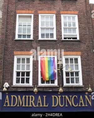 An den Fenstern über dem Admiral Duncan Pub in der Old Compton Street, Soho, London hängen nach den Dreharbeiten im Nachtclub Pulse, Orlando, USA, schwule Flaggen. Am 30. April 1999 war der Admiral Duncan Schauplatz einer Nagellackbombenexplosion, bei der drei Menschen ums Leben kamen und um 70 vom Neonazi David Copeland verwundet wurden. Stockfoto