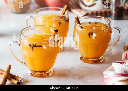 Heiß gewürzt Glühwein Apfelwein in Gläsern mit Zimt Sticks und andere Gewürze im Hintergrund auf Marmor Zähler Stockfoto