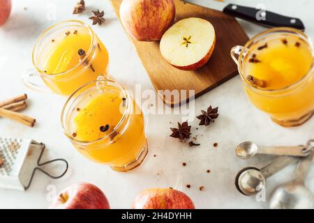 Heiß gewürzt Glühwein Apfelwein in Gläsern mit Zimt Sticks und andere Gewürze im Hintergrund auf Marmor Zähler Stockfoto