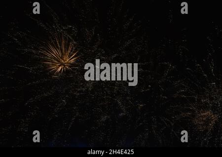 Dunkler Nachthimmel mit Feuerwerk in gelben Farben. Stockfoto