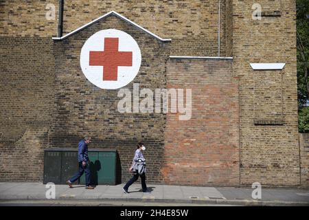 Eine Frau mit Gesichtsmaske geht an einem Gebäude des Britischen Roten Kreuzes in Dalston, Hackney, im Osten Londons, vorbei, während Großbritannien weiterhin im Lockdown ist, um die Ausbreitung des Coronavirus einzudämmen. Bilddatum: Samstag, 2. Mai 2020. Stockfoto