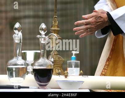 Revd Christopher Owens verwendet Handdesinfektionsmittel während einer anglikanischen eucharistie live auf facebook für die Gemeindemitglieder aus dem Hintergarten der St. Michael and All Angels Kirche in Walthamstow, Nordost-London. Bilddatum: Sonntag, 3. Mai 2020. Stockfoto