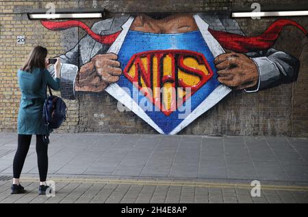 Eine Frau fotografiert ein NHS-Superman-Graffiti des Straßenkünstlers Lionel Stanhope, um den Beschäftigten des NHS von Waterloo, London, Tribut zu zollen, während Großbritannien weiterhin in der Blockierung ist, um die Ausbreitung des Coronavirus einzudämmen. Bilddatum: Freitag, 8. Mai 2020. Stockfoto