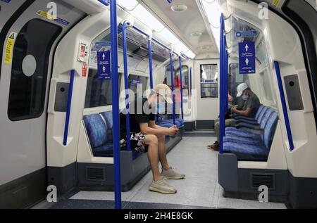 Pendler, die eine Gesichtsmaske tragen, während sie in einem U-Bahn-Zug der Piccadilly Line in London unterwegs sind, während die Regierung beginnt, einige Sperrmaßnahmen in England zu lockern. Bilddatum: Montag, 1. Juni 2020. Stockfoto