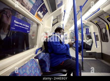 Pendler, die eine Gesichtsmaske tragen, während sie in einem U-Bahn-Zug der Piccadilly Line in London unterwegs sind, während die Regierung beginnt, einige Sperrmaßnahmen in England zu lockern. Bilddatum: Montag, 1. Juni 2020. Stockfoto