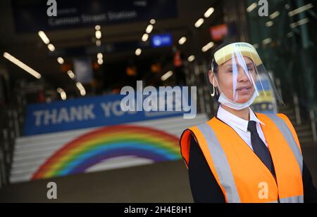 Ein Arbeiter, der ein Visier als persönliche Schutzausrüstung trägt, steht vor der Cannon Street in London, wo auf den Stufen des Bahnhofs ein Regenbogen gezeigt wurde, um der Arbeit des britischen NHS (National Health Service) zu danken, während die Regierung beginnt, einige Sperrmaßnahmen in England zu lockern. Bilddatum: Montag, 1. Juni 2020. Stockfoto