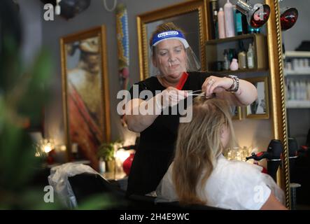 Ein Friseur mit einem Gesichtsschutz bei der Arbeit in einem Friseursalon im Zentrum von London, als Friseure und Schönheitssalons ihre Türen zum ersten Mal seit drei Monaten öffneten, nachdem sich die Einschränkungen der Coronavirus-Sperre stark entspannt hatten. Bilddatum: Sonntag, 5. Juli 2020. Stockfoto