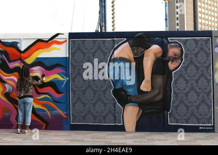 Ein Künstler malt ein Wandbild neben einem Kunstwerk (rechts) des Straßenkünstlers Lionel Stanhope auf einem Horten in der Nähe des Bahnhofs Lewisham. Das Kunstwerk zeigt Patrick Hutchinson, der im vergangenen Juni bei einem Streit um einen Protest gegen Black Lives Matter eintrat und einen verletzten weißen Mann rettete. Bilddatum: Montag, 31. August 2020. Stockfoto