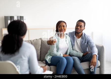 Afroamerikanisches Ehepaar, das sich nach einer wirksamen Psychotherapie im Büro des Familienberaters umarmte Stockfoto