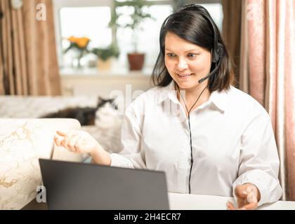 Frau konsultiert per Videoverbindung mit Headset mit Laptop. Geschäftsfrau mit Videokonferenz mit Geschäftspartner auf Notebook. Frau mit Computer V Stockfoto