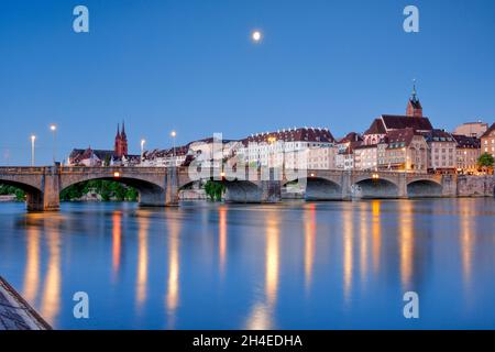 Blick vom Rheinufer entlang der Flusspromenade auf die nächtlich beleuchtete Altstadt von Basel mit dem Basler Münster, der Martins Kirche, der Mittle Stockfoto