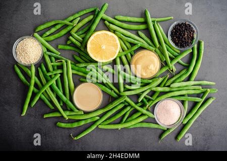 Dijon Tahini Grüne Bohnen Zutaten: Rohe String-Bohnen, dijon-Senf und andere Zutaten Stockfoto