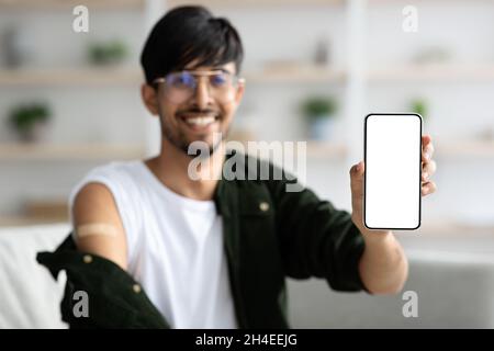 Glücklicher indischer Mann zeigt Smartphone mit leerem Bildschirm Stockfoto