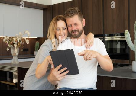 Nahaufnahme eines glücklichen, liebenden jungen Paares in der Küche zu Hause mit einem Tablet Stockfoto