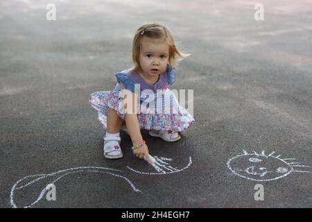 Oben Aufnahme eines kleinen Mädchens, das in farbenfroher Kreide auf dem Bürgersteig kritzelte Stockfoto