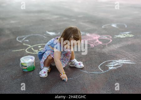 Oben Aufnahme eines kleinen Mädchens, das in farbenfroher Kreide auf dem Bürgersteig kritzelte Stockfoto