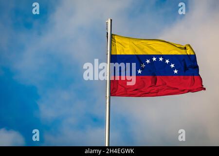 Eine Flagge Venezuelas, die auf einem Fahnenmast gegen den Himmel fliegt Stockfoto