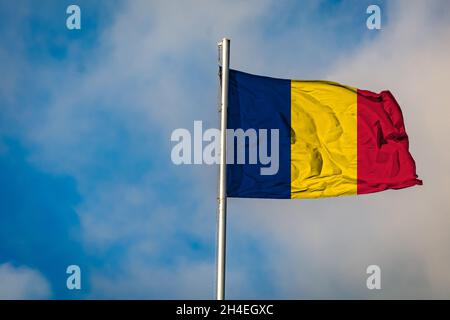Eine Flagge des Tschad, die auf einem Fahnenmast gegen den Himmel fliegt Stockfoto