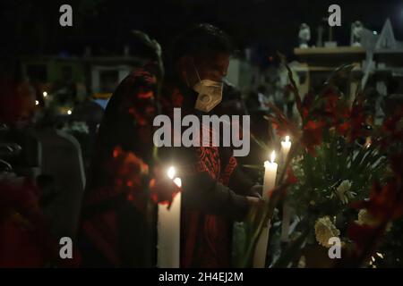 Eine Person hält einen Abend auf dem Friedhof von San Pedro Tláhuac ab, um die Ankunft ihrer verstorbenen Angehörigen zu erwarten, Verwandte schmücken Blumen, Bringen Sie ihnen Essen und singen Sie ihnen an den Gräbern als mexikanische Traditionen des Tages der Toten, um ihnen eine gute Rückkehr auf dem Weg nach Mictlan zu wünschen. Am 1. November 2021 in Mexiko-Stadt, Mexiko. (Foto von Fernanda Rojas/ Eyepix Group) Stockfoto