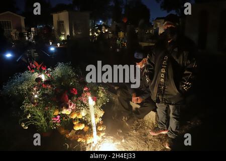 Eine Person hält einen Abend auf dem Friedhof von San Pedro Tláhuac ab, um die Ankunft ihrer verstorbenen Angehörigen zu erwarten, Verwandte schmücken Blumen, Bringen Sie ihnen Essen und singen Sie ihnen an den Gräbern als mexikanische Traditionen des Tages der Toten, um ihnen eine gute Rückkehr auf dem Weg nach Mictlan zu wünschen. Am 1. November 2021 in Mexiko-Stadt, Mexiko. (Foto von Fernanda Rojas/ Eyepix Group) Stockfoto