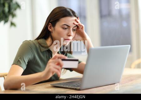 Besorgte Frau, die zu Hause Probleme beim Online-Kauf mit Kreditkarte und Laptop hat Stockfoto