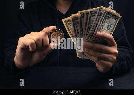 Geld und Gold doge Münzen in schwarzer Haube Männerhand, Krypto Stockfoto