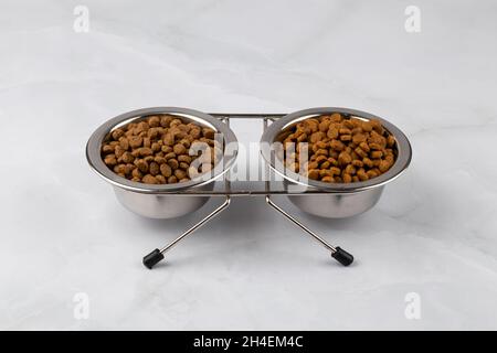 Zwei Stahlschüsseln mit pelletiertem Katzenfutter. Hundeschale mit Tierfutter für Hunde. Trockenes Hundefutter. Eine Tasse Kibbles für Haustiere Stockfoto
