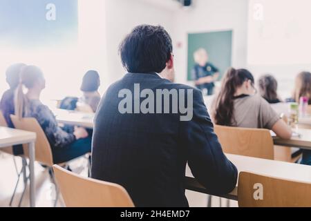 Lehrer an der Universität vor einem Whiteboard-Bildschirm. Schüler hören um zu belehren und sich Notizen macht. Stockfoto